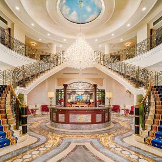 A luxurious hotel lobby featuring a grand staircase and an ornate chandelier.