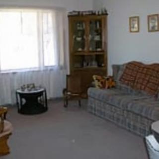 A cozy living room featuring a plaid sofa, a coffee table, and a wooden cabinet by the window.