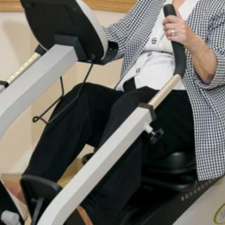 A person using indoor exercise equipment, possibly for rehabilitation or fitness purposes.
