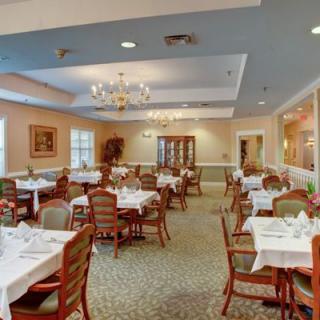 An elegant dining room with neatly arranged tables and chairs, adorned with chandeliers.
