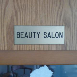 A plaque sign indicating a beauty salon on a wooden surface.
