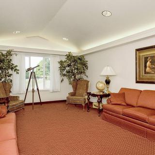 A cozy living room with matching sofas, armchairs, and a telescope by the window.