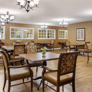 A well-lit dining area with elegant chairs and tables on wooden flooring.