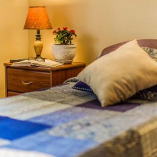 A cozy bedroom with a quilted bed, nightstand, and lamp.
