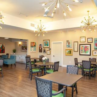 A modern dining room with eclectic artwork, stylish chandeliers, and neatly arranged tables and chairs.