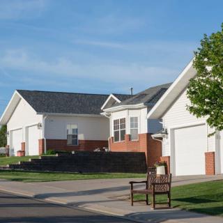 A quiet suburban street lined with modern single-story houses featuring driveways and front lawns.