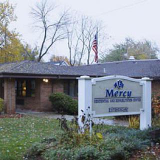 A healthcare facility named Mercy with a visible sign and surrounding autumn foliage.