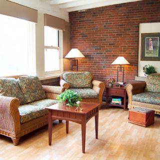 A cozy living room with sofas, lamps, and a wooden coffee table against a brick wall.
