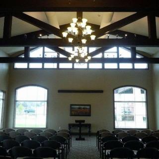 Interior view of a chapel with rows of seating and large windows allowing natural light.