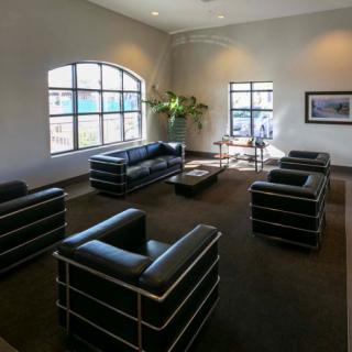 A modern waiting area featuring black leather sofas and minimalist decor.