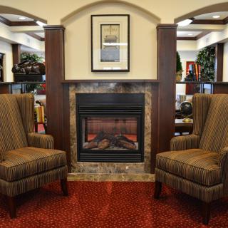 A cozy seating area with two armchairs flanking a fireplace in a warmly decorated room.