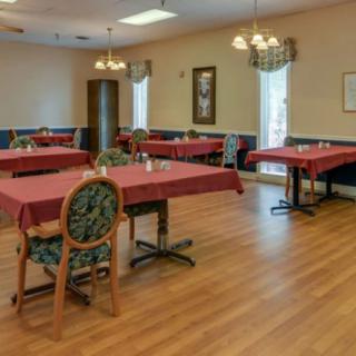 An empty dining room with neatly arranged tables and chairs, decorated with chandeliers.