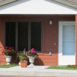 A small house with a front porch and flower pots.