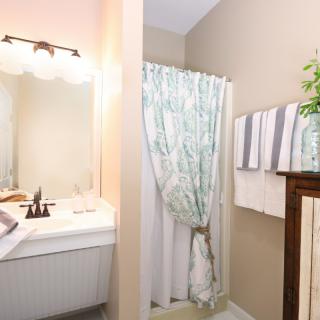 A cozy bathroom with a sink, mirror, and a shower area featuring a floral curtain.