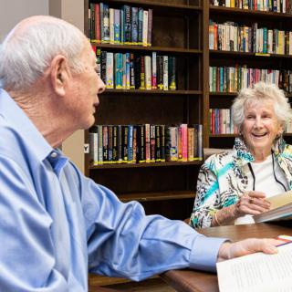 Elderly couple engaged in a lively discussion at the library.