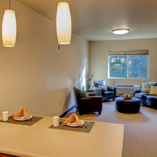 A modern living space featuring a cozy seating area and a small dining table under stylish pendant lights.