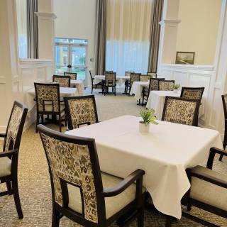 A well-arranged dining room with tables covered in white tablecloths and elegant chairs.