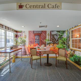 A cozy seating area inside the Central Cafe, featuring a table with chairs and lush decorations.