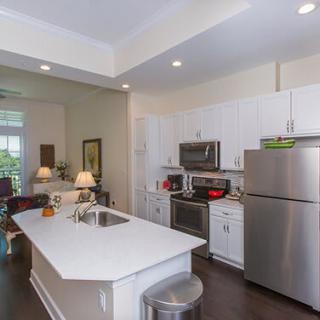 A modern kitchen featuring stainless steel appliances and white cabinetry, complete with a center island and recessed lighting.