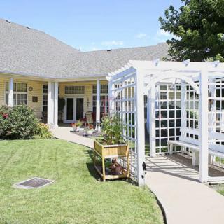 A charming house with a well-maintained lawn and a pergola.