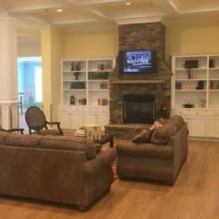 A cozy living room with sofas, a fireplace, and built-in bookshelves.