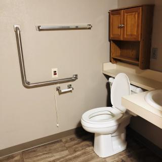 An accessible bathroom featuring a toilet, sink, and grab bars for support.