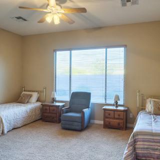 A cozy bedroom with two single beds, an armchair, and a large window.