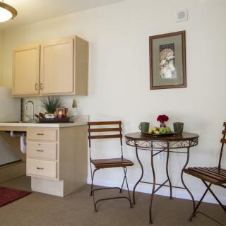 A cozy kitchen corner with a small table and chairs, decorated with flowers.