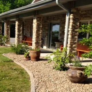 A neatly landscaped garden with a stone walkway and planters in front of a house.