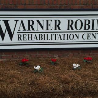 Sign for Warner Robins Rehabilitation Center with flowers in the foreground.