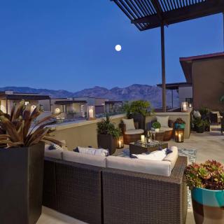 A luxurious outdoor patio with comfortable seating, overlooking mountains under a moonlit evening sky.