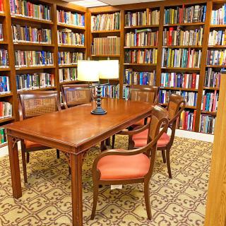A cozy library corner with a wooden table surrounded by bookshelves.