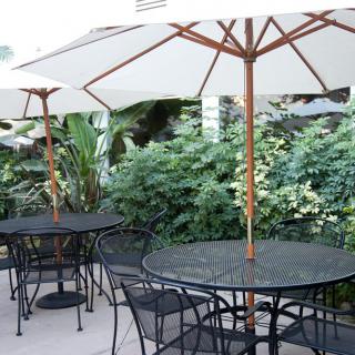 Outdoor patio area with tables, chairs, and umbrellas surrounded by greenery.