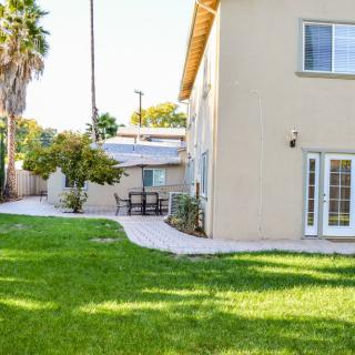 A backyard view of a house featuring a well-maintained lawn and a patio area.