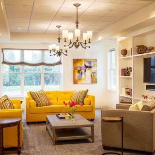 A modern living room featuring bright yellow sofas and a stylish chandelier, creating a cozy and inviting atmosphere.