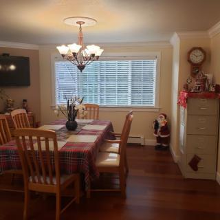 A cozy dining room with a large table, surrounding chairs, and a decorative chandelier, adorned with festive decorations.