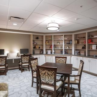A well-organized study area featuring bookshelves, a central table surrounded by chairs, and computers along the wall.