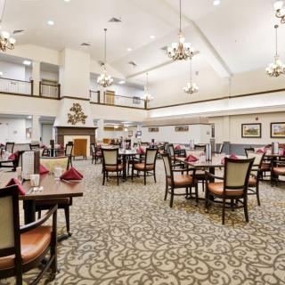 A spacious and elegantly decorated dining room with set tables and chandeliers.
