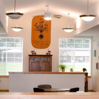 A cozy dining area with wooden furniture and pendant lighting, featuring large windows and minimalistic decor.