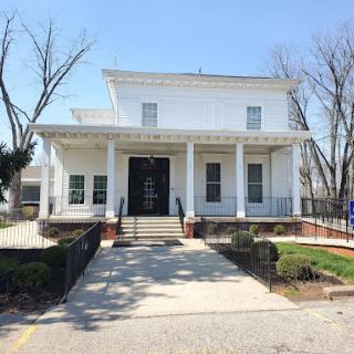 A charming white house featuring a classic porch and well-maintained landscaping.