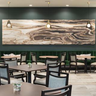 Modern restaurant dining area with abstract artwork and pendant lighting.