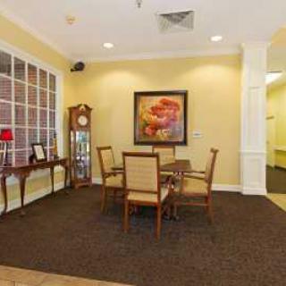 A cozy room featuring a wooden dining table with chairs, a colorful painting on the wall, and a grandfather clock in the corner.
