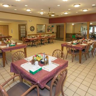 An empty dining room with tables and chairs arranged neatly, ready for guests.
