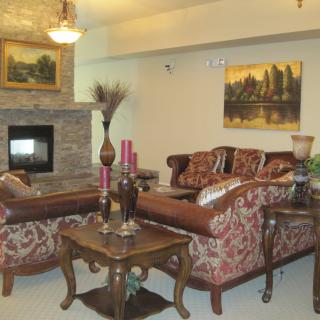 A cozy living room with ornate sofas, a stone fireplace, and elegant decor.