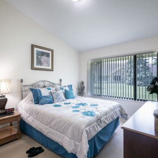 A cozy, well-lit bedroom with a large bed and decorative elements, offering a view through wide windows.