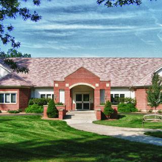 A charming brick building surrounded by well-maintained greenery and a clear blue sky.