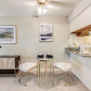 A modern dining space with a glass table and minimalist decor adjacent to a kitchen counter.