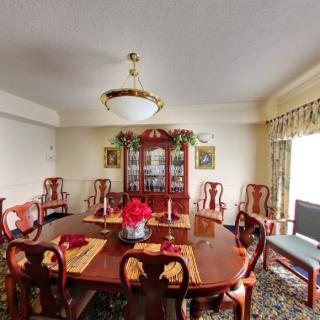 A traditional dining room with a wooden table and chairs, adorned with a chandelier and decorative elements.