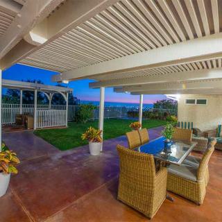 A cozy patio area with wicker furniture and a glass table, overlooking a scenic sunset.