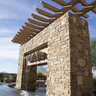 A stone structure with a wooden pergola and a cascading water feature.